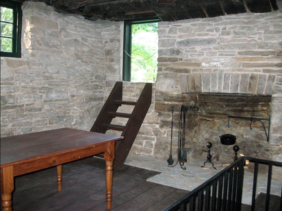 Room in a stone building with furniture and stone oven.