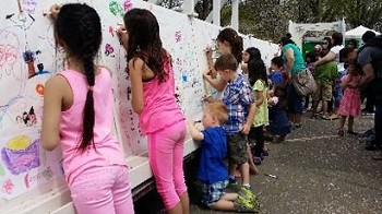 Group of kids coloring a mural on a wall