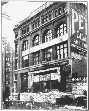 Three story 19th Century building with goods stacked outside.