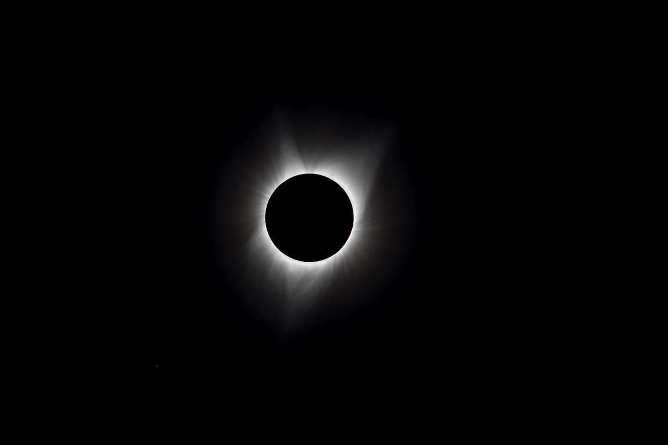 Luminous wisps of the sun's corona rim the darkened sun in this view of the 2017 total solar eclipse.