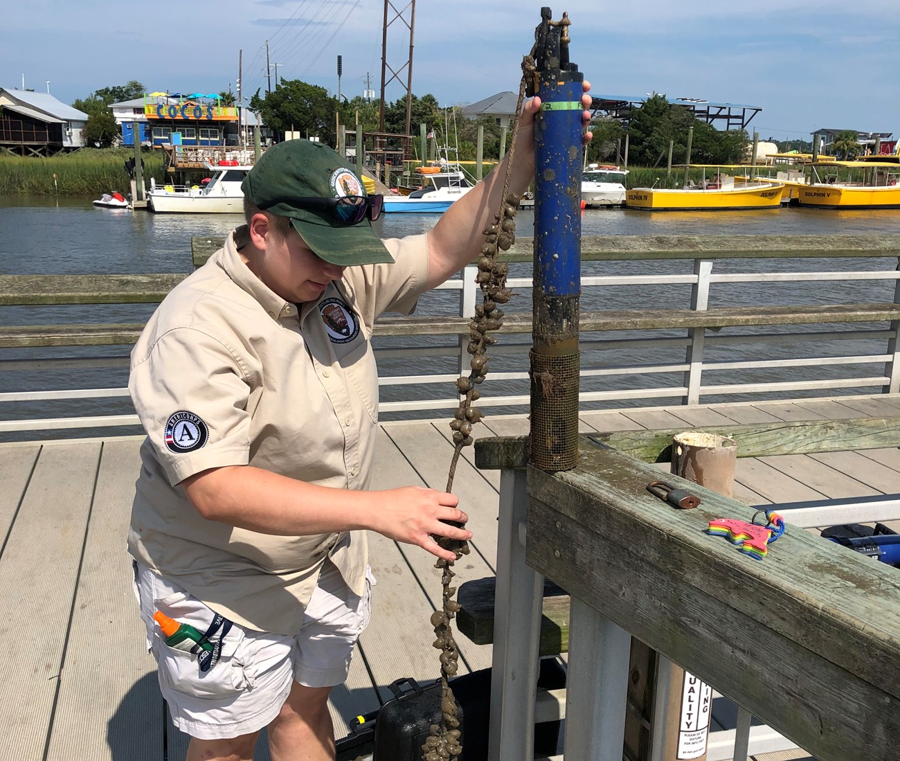 Person cleans off a data sonde standing on a dock