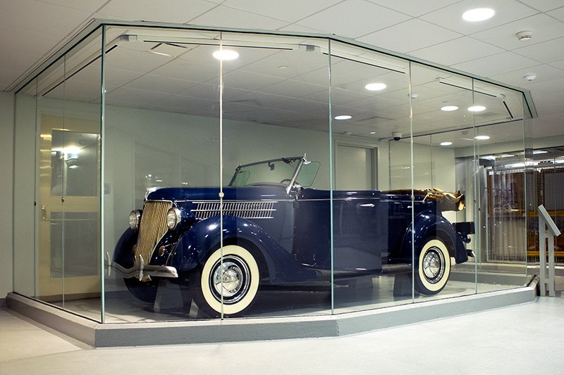 A convertible automobile behind a glass wall.
