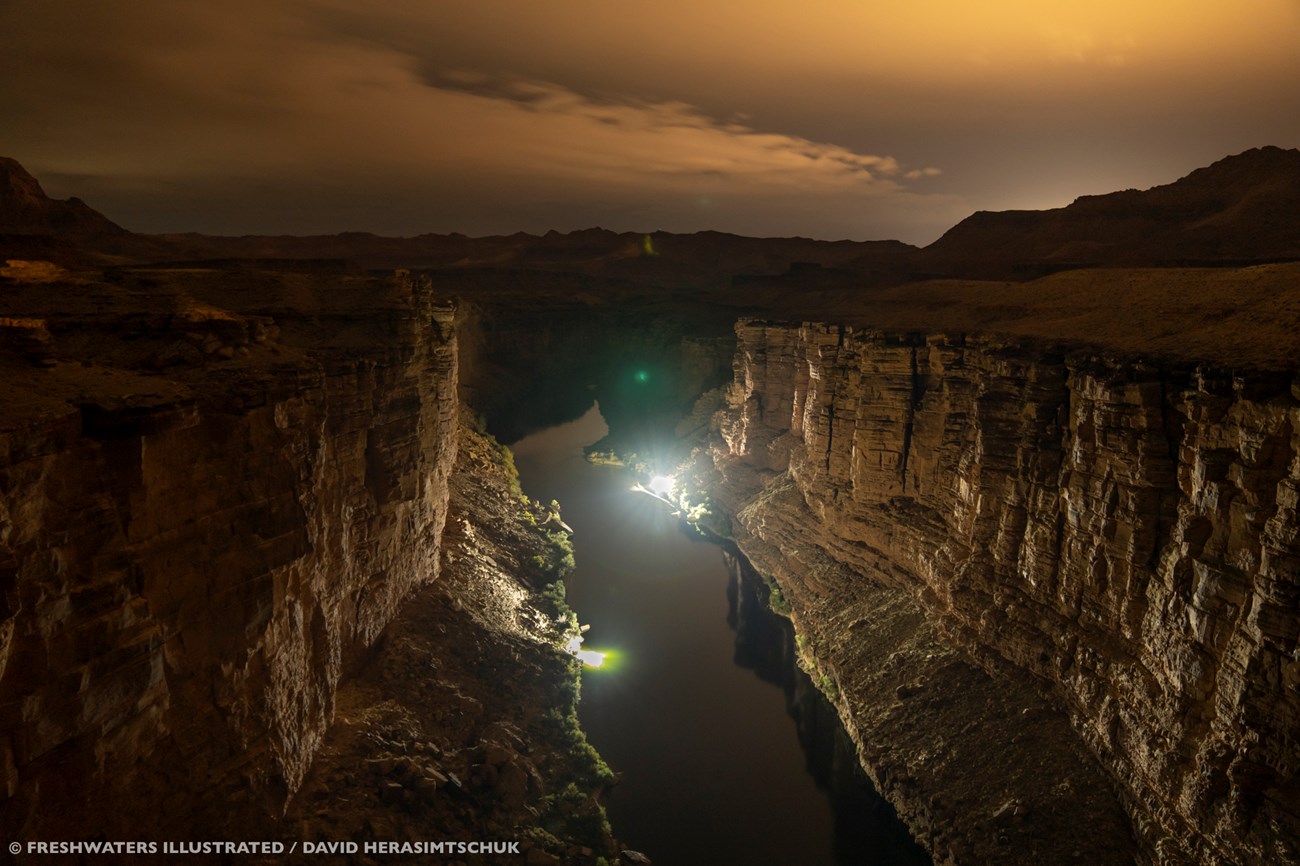 A wide shot of the Grand Canyon, with bright lights illuminating the canyon walls.