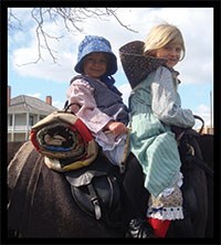 Two girls with blonde hair on a horse