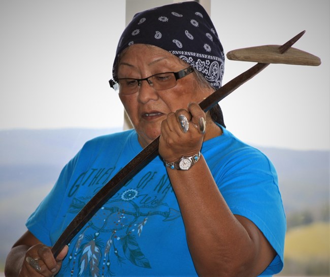 Woman holding tukes (digging stick).