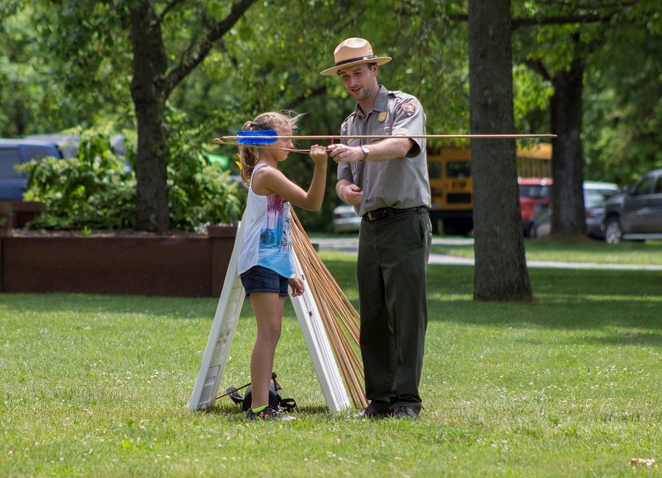 Ranger instructing kid on how to throw a spear using an atlatl