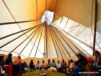 Members of the Inter-tribal Buffalo Council sit together inside a large teepee