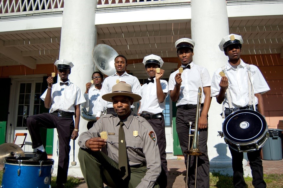 Ranger and youth brass band holding Junior Ranger badges