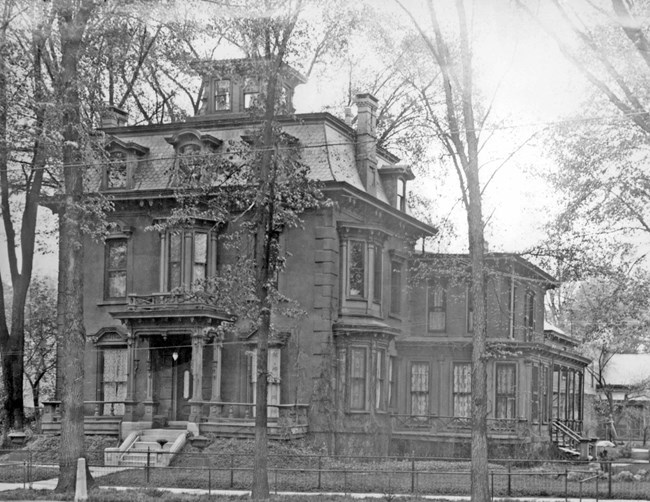 An old black and white photo of a victorian mansion with a distinct squared-off roof.