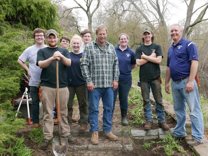 High School students and teachers with tools pose for outdoor photo.