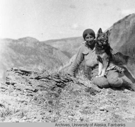 a woman sitting on a mountain top with a dog