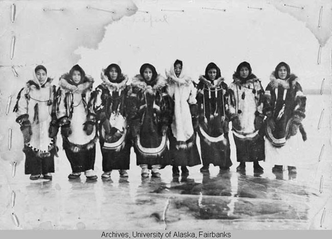 A group of Alaska Natives wearing furs look into the camera