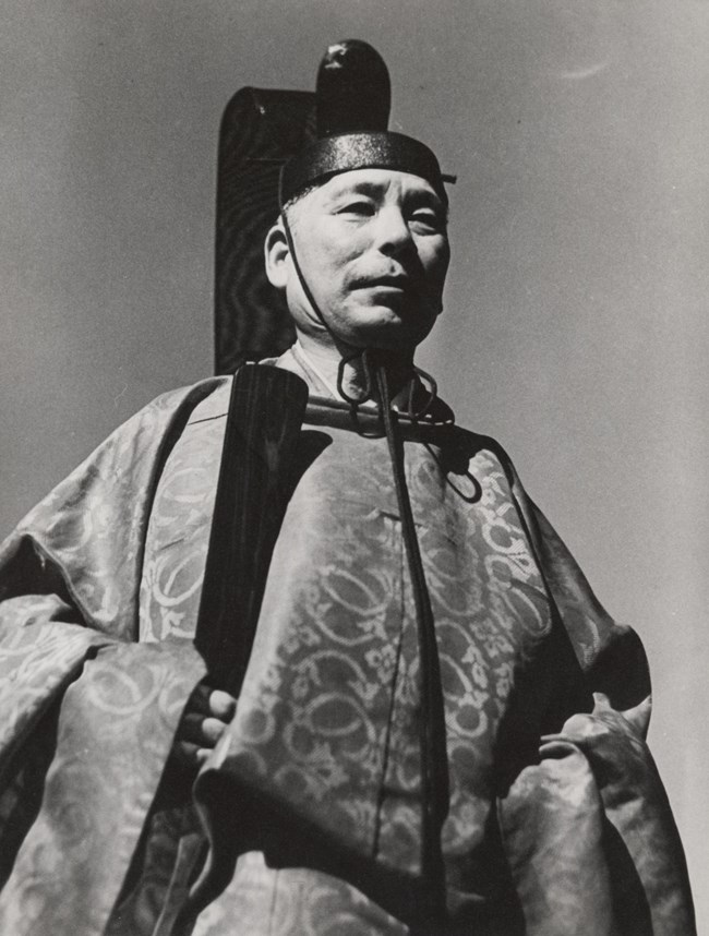 A black and white portrait shows Shinto priest Reverend Sakuichi Sutow in ceremonial dress.