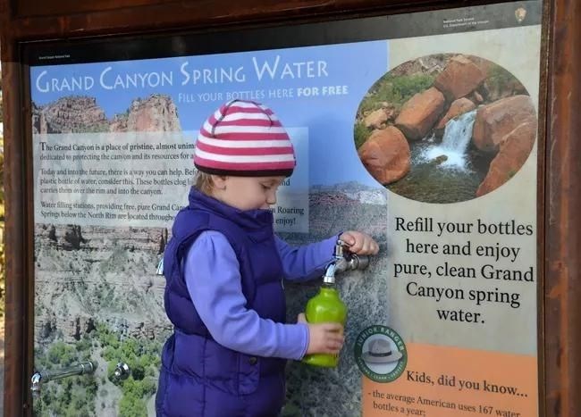 A child fills up a water bottle using a water station at Grand Canyon National Park.