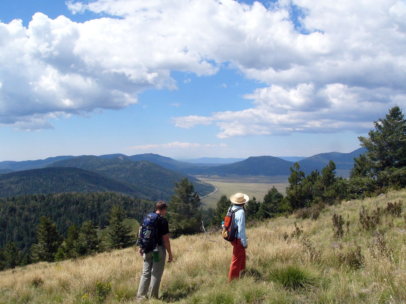 VALL visitors looking from erro grande area across caldera landscape NPS photo hikers on hill slope with valley and hills in background