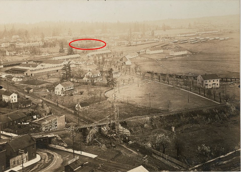 Black and white aerial photo of Vancouver Barracks with one building in the center of the image circled in red.