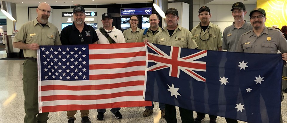 A group of men and women hold US and Australian flags.