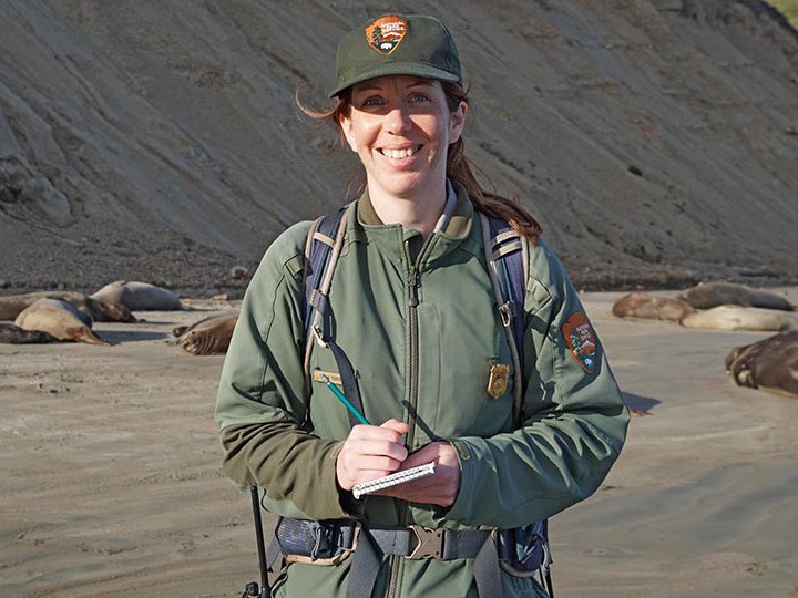 Portrait of Marine Ecologist Sarah Codde, smiling while surveying elephant seals on Drake's beach in Point Reyes.