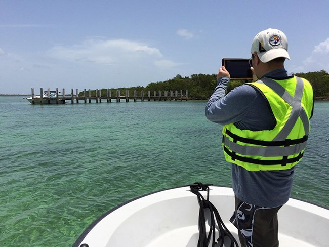 An employee uses GeoJot to take a picture of a dock while standing on a boat.