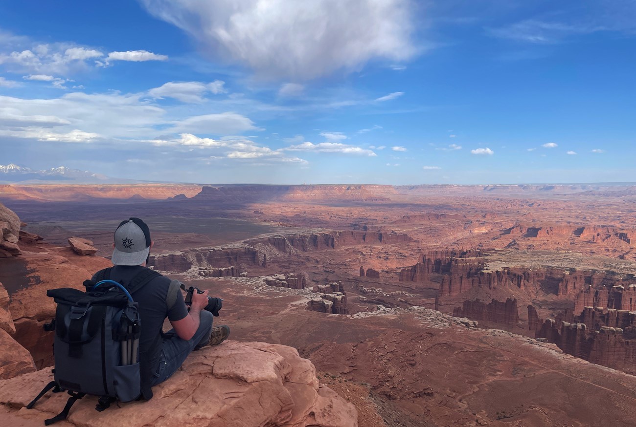 grand view point Photo of a seated person looking over a vast expanse of canyon country