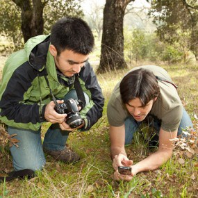 Two people using an app on a cell phone to take a photo of plants