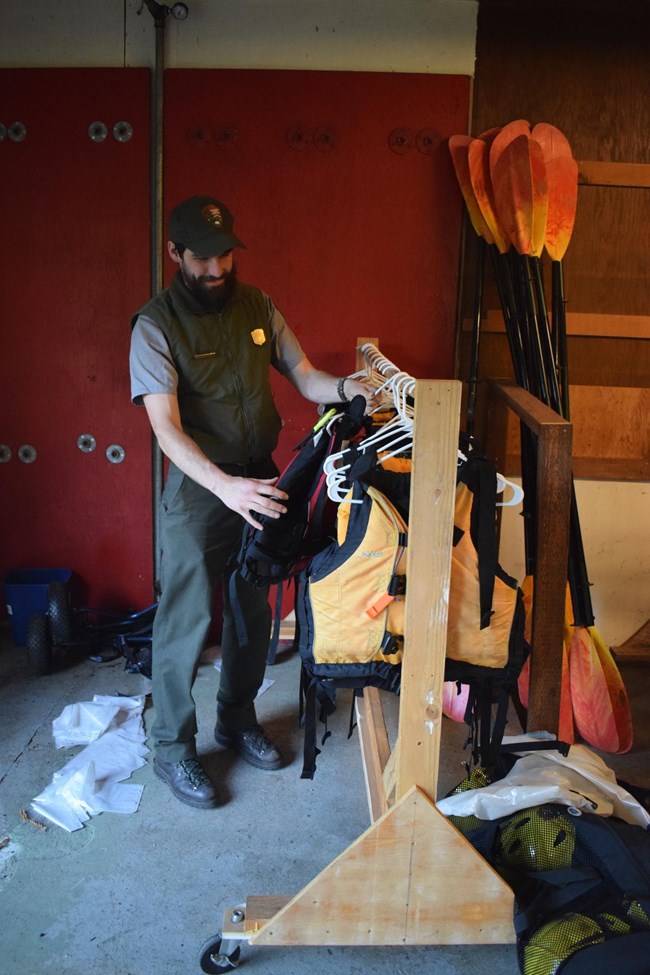 park ranger organizing life jackets in a storage room.