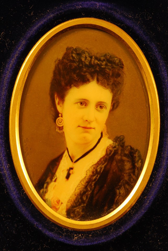 Colored black and white photograph of woman wearing ornate dress and jewelry