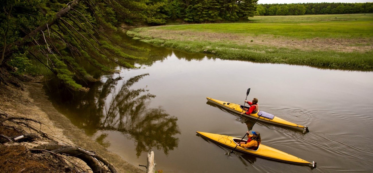 Kayakers paddle past extensive salt marshes along the York River in Maine