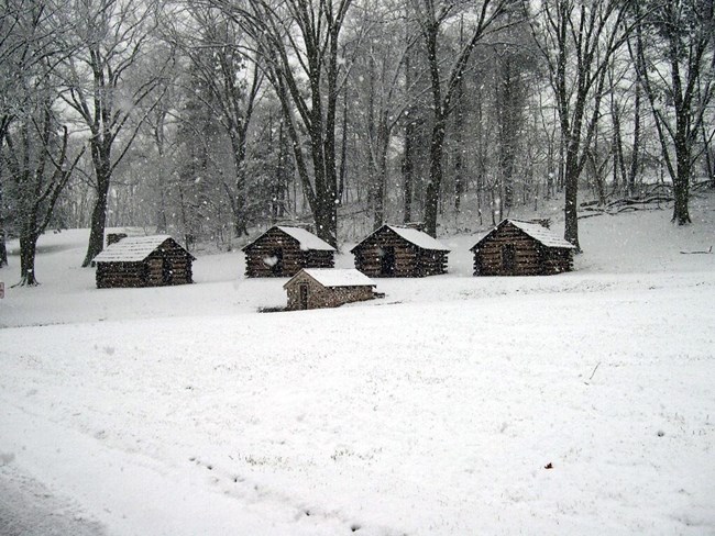 Reconstructed soldier cabins in the snow at Valley Forge. NPS