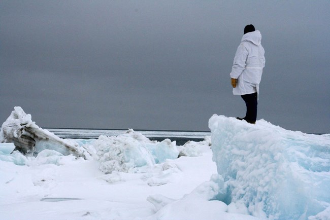 An Alaskan Native looks out over the Arctic Ocean/Chukchi Sea in the winter from sea ice.