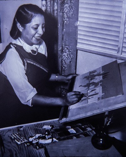 A black and white photo of a woman painting.