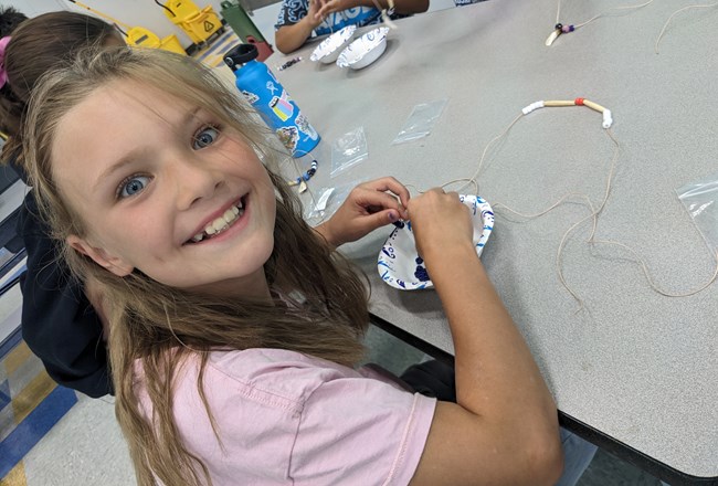 Girl making necklace with beads