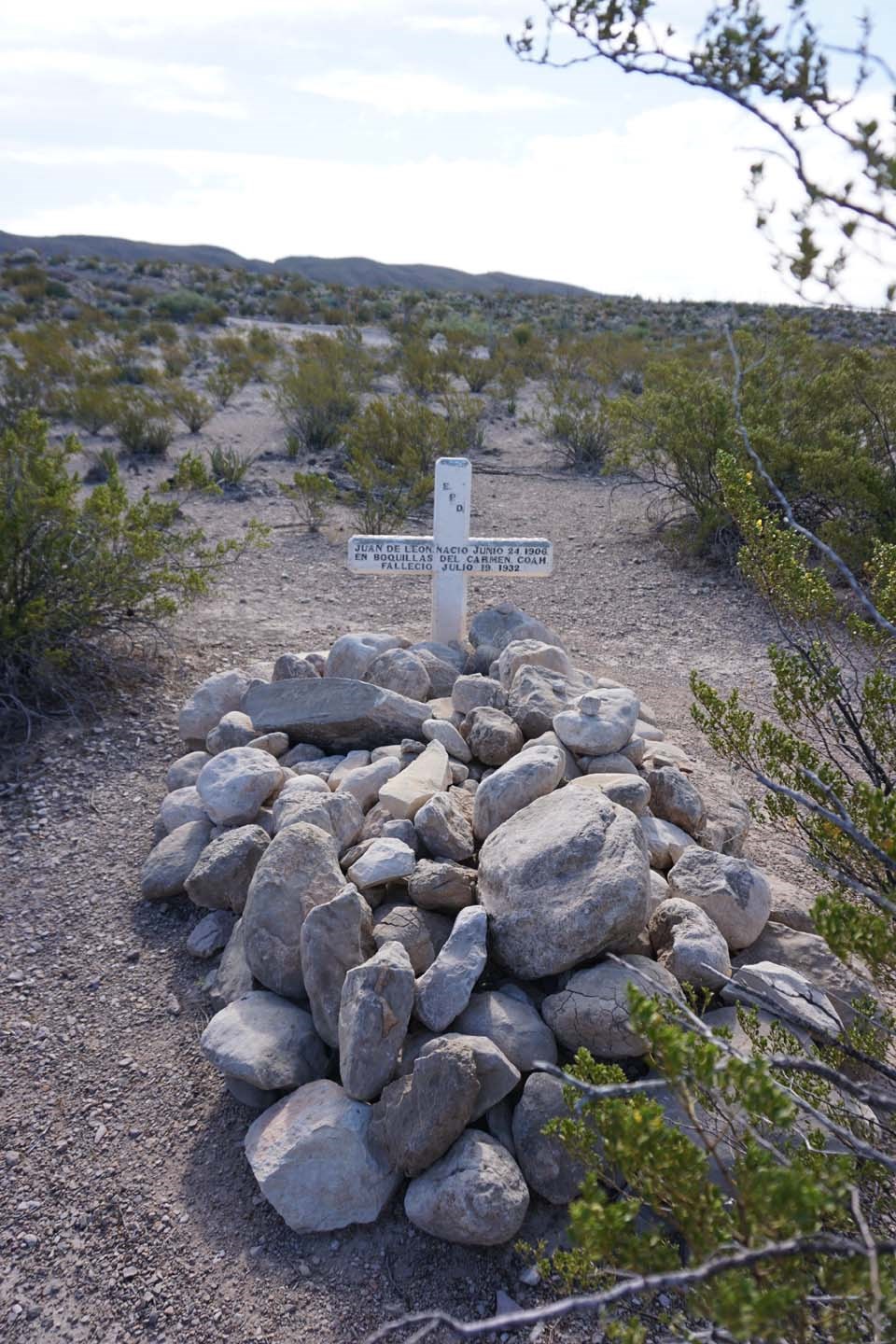 Grave A cross headstone marks a grave with rocks piled on it.