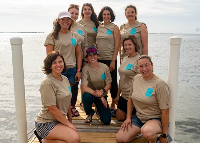9 women in matching t shirts posing on a dock