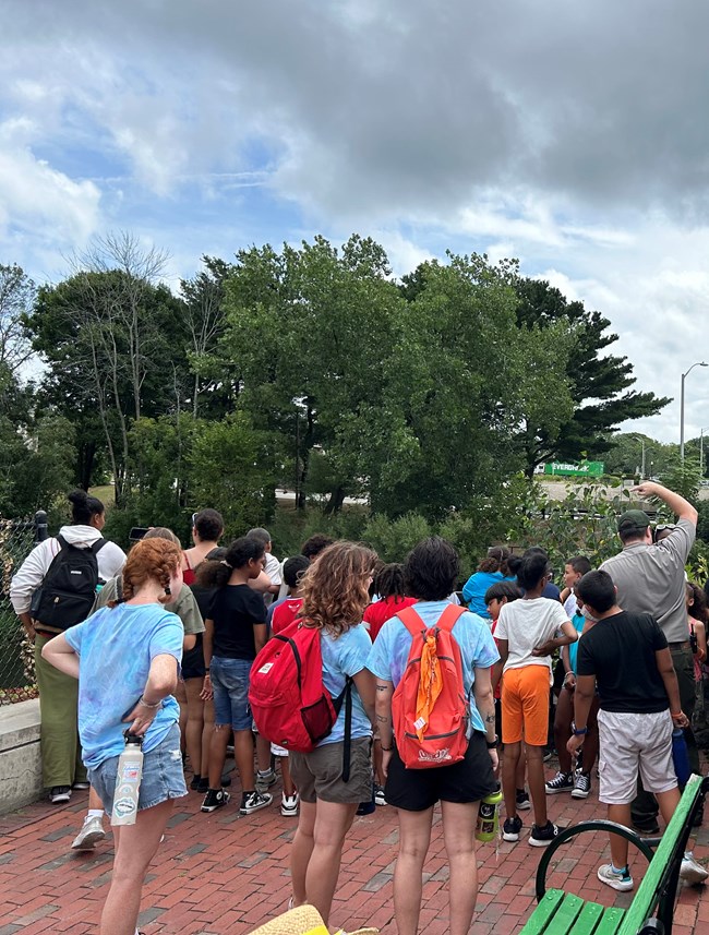 a ranger talks to a group of students by the falls