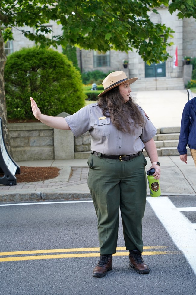 a female ranger in uniform stops traffic in a street