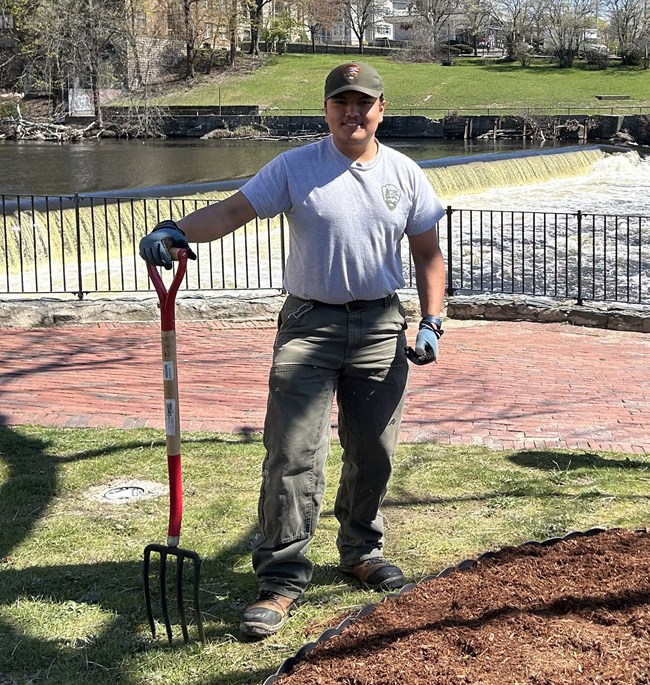 Man standing with gardening tools in front of Blackstone River