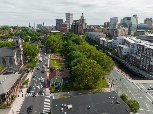 a view of the green park and the park's visitor center with the city in the background