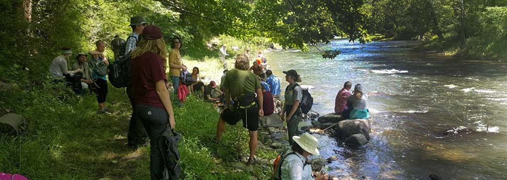 ranger and hikers stop for a break along a river