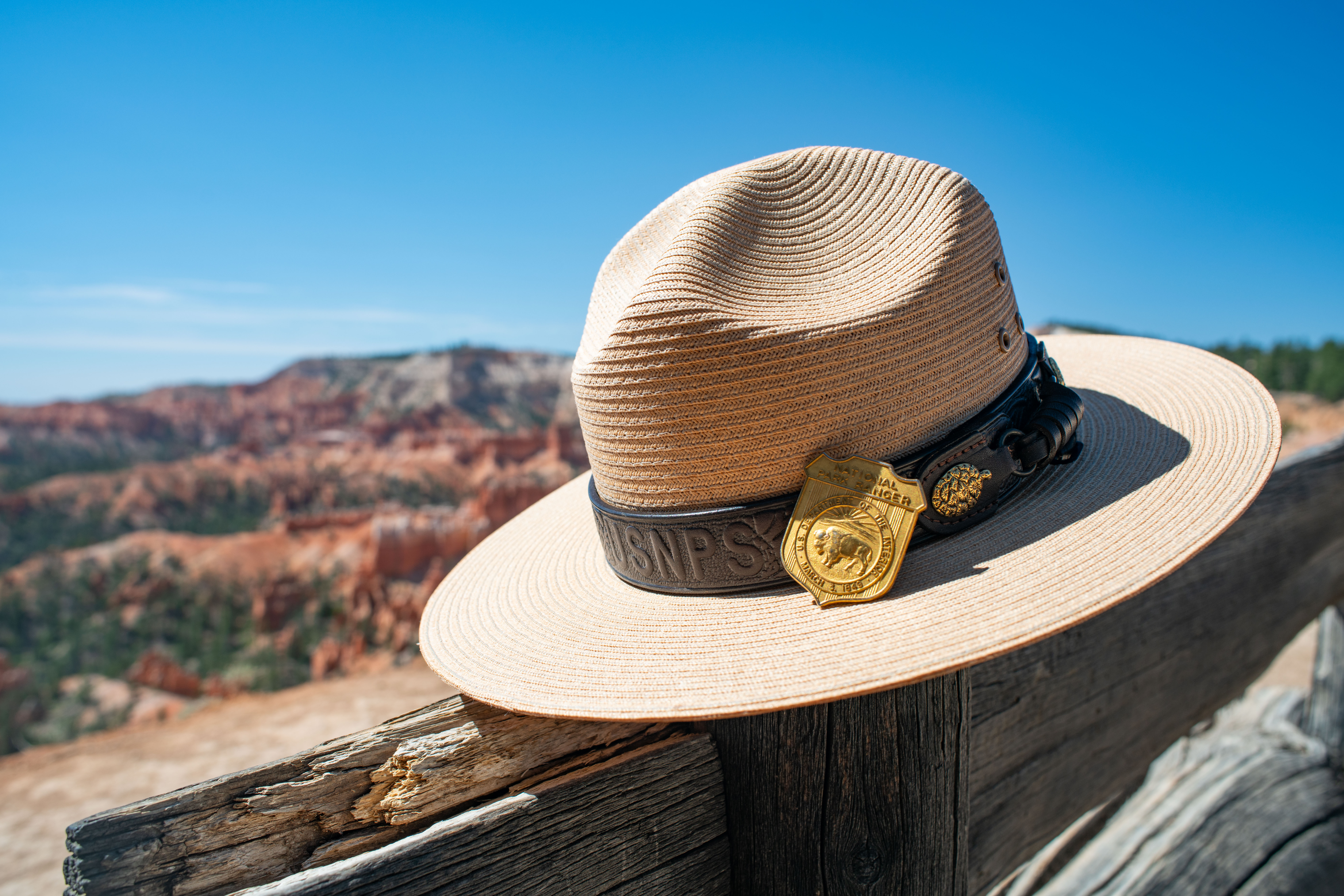 A national park service ranger hat and badge rests on a wooden bench