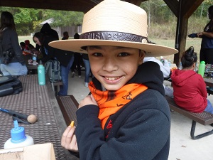 Boy wearing ranger hat eating at picnic table