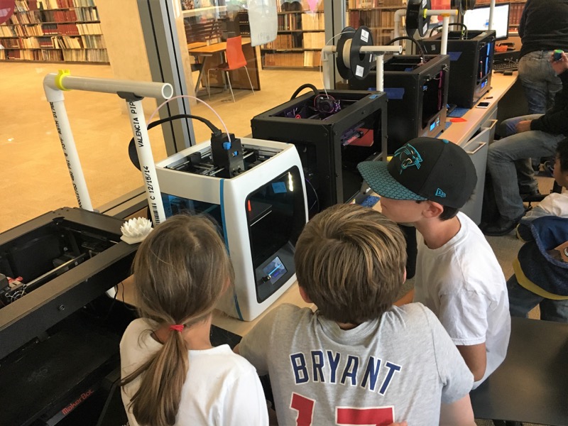 a group of students watch as a 3D printer works on a print at the Downtown Public Library Innovation Lab.