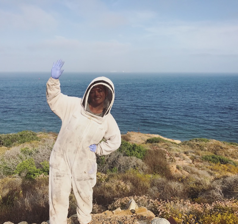 Hilary waves on the cliffs in her bee suit
