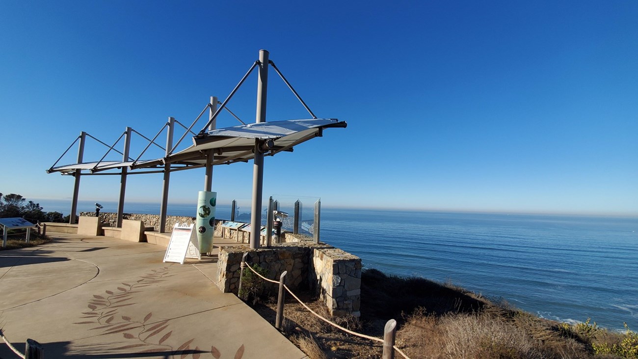 A metal structure used for shelter overlooks the ocean.