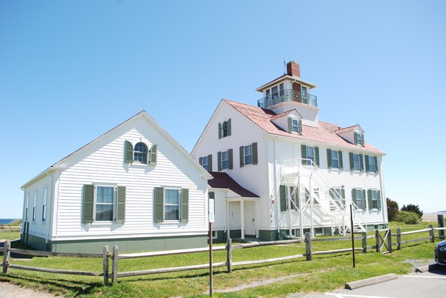 White building with green shutters and red roof.