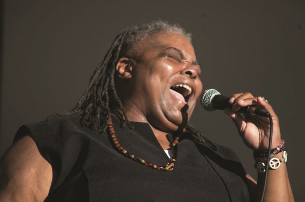 A woman sings enthusiastically into a microphone.