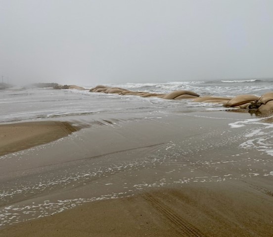 Ocean water across a sand covered highway.