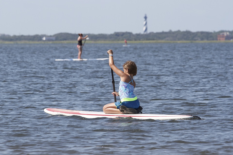 Visitors enjoying the Pamlico Sound with Cape Hatteras Lighthouse visible in the distance.