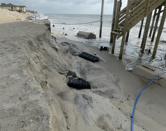 Photo showing erosion and hazards on the beach next to houses.