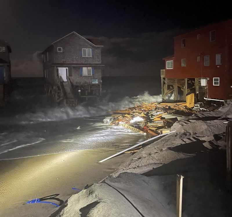 Nighttime photo of debris on the beach near houses.